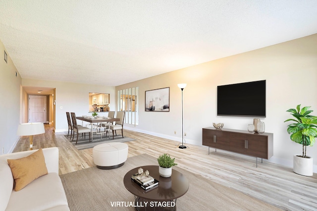 living area featuring a textured ceiling, baseboards, and wood finished floors