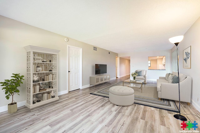 living room featuring wood finished floors, visible vents, and baseboards