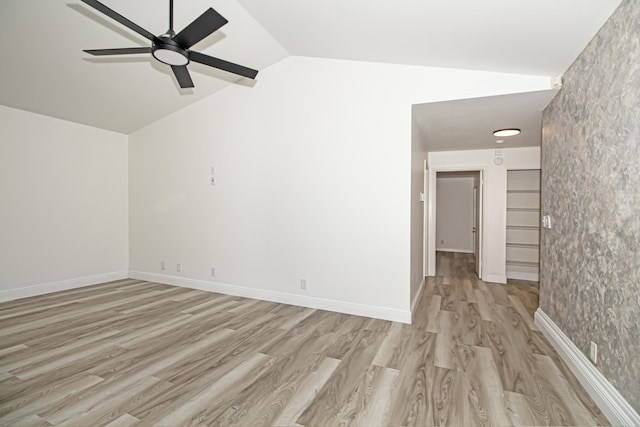 empty room with ceiling fan, lofted ceiling, and light hardwood / wood-style flooring