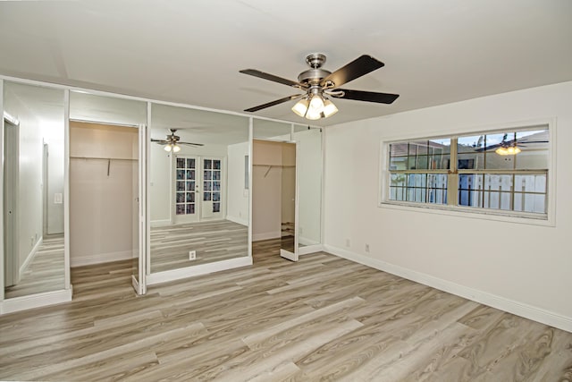 unfurnished bedroom featuring multiple closets, ceiling fan, and light hardwood / wood-style flooring