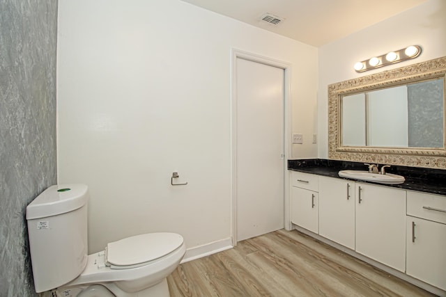 bathroom with hardwood / wood-style flooring, vanity, and toilet