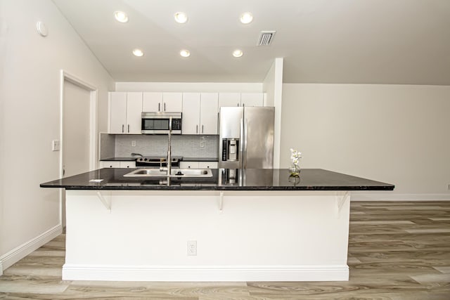 kitchen with a breakfast bar, white cabinetry, an island with sink, sink, and stainless steel appliances