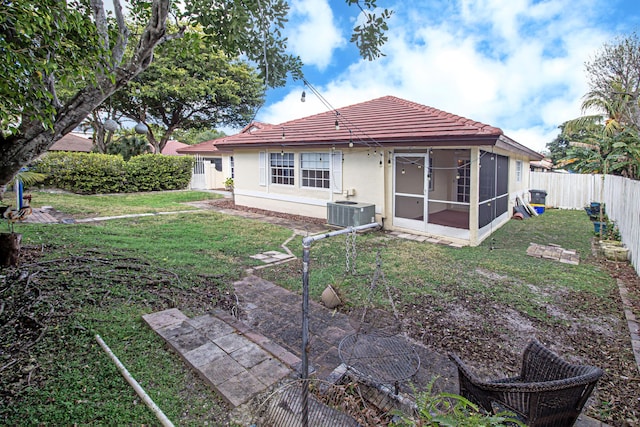 back of property with central AC, a sunroom, and a lawn