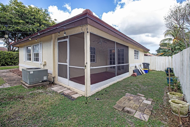 rear view of house featuring a sunroom, a yard, and central air condition unit