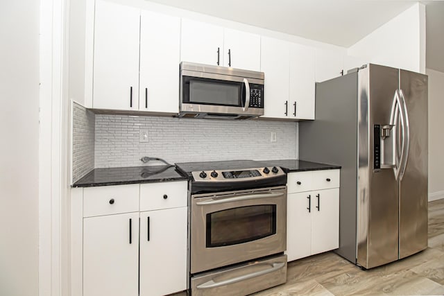 kitchen with backsplash, appliances with stainless steel finishes, dark stone counters, and white cabinets