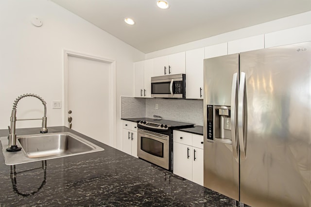 kitchen featuring vaulted ceiling, sink, white cabinets, backsplash, and stainless steel appliances