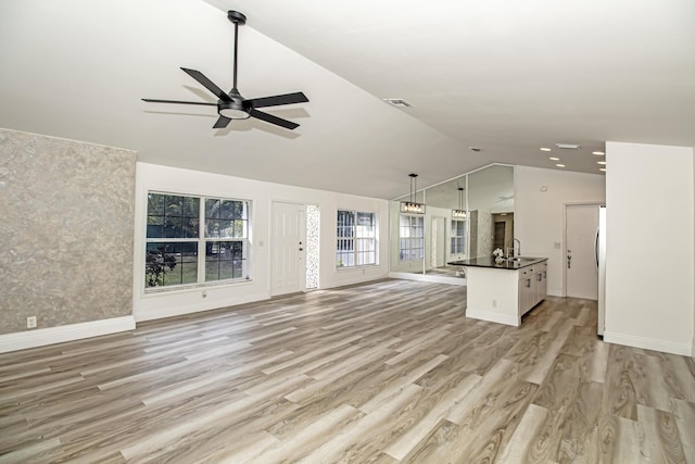 unfurnished living room with lofted ceiling, sink, ceiling fan, and light hardwood / wood-style flooring