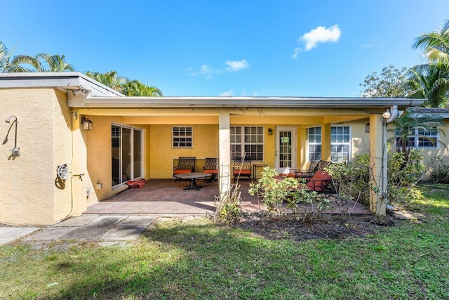 rear view of property with a lawn and a patio