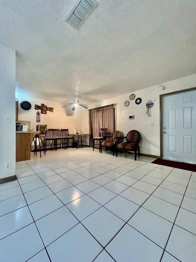 interior space with light tile patterned floors, a textured ceiling, visible vents, and a ceiling fan