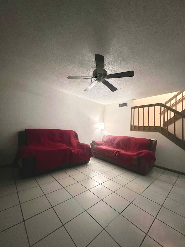 living room with light tile patterned floors, stairway, visible vents, and a textured ceiling