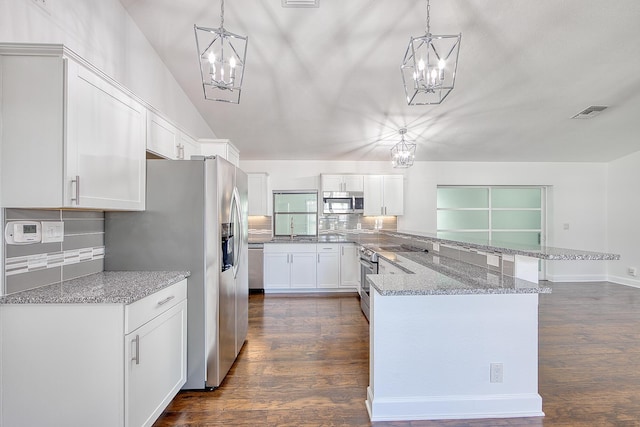 kitchen featuring dark wood finished floors, a notable chandelier, stainless steel appliances, white cabinetry, and a peninsula