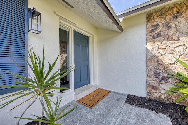 entrance to property featuring stone siding and stucco siding