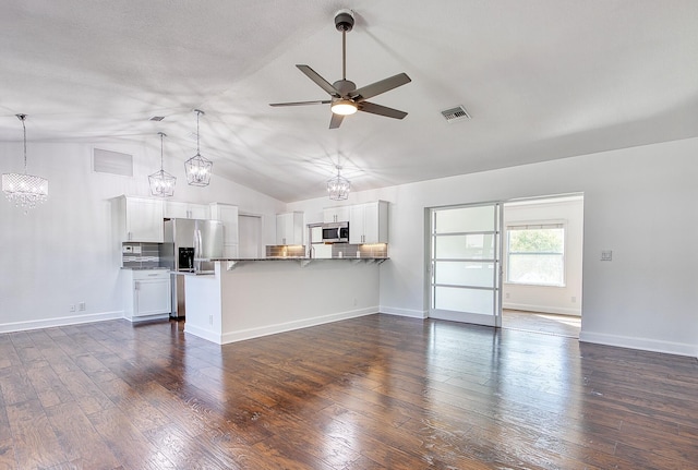 unfurnished living room with lofted ceiling, ceiling fan with notable chandelier, dark wood-style flooring, visible vents, and baseboards