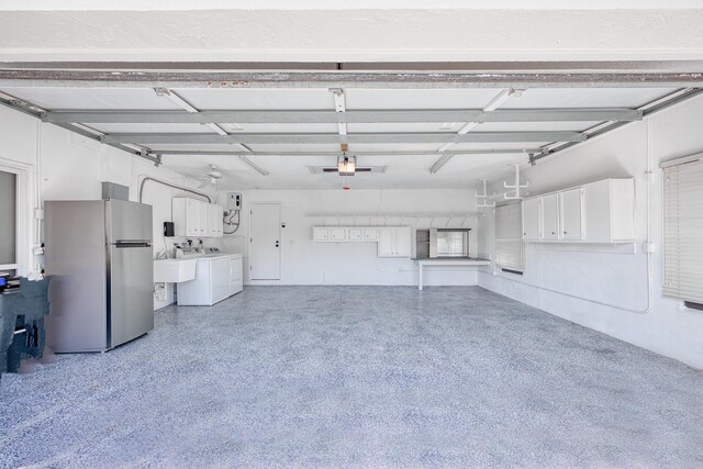 garage featuring a sink, freestanding refrigerator, and washer and dryer