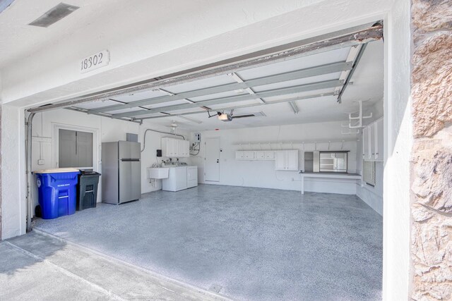 garage with washer and dryer, freestanding refrigerator, a sink, and a garage door opener