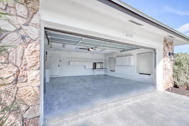 garage featuring a sink, a garage door opener, electric panel, freestanding refrigerator, and washing machine and clothes dryer