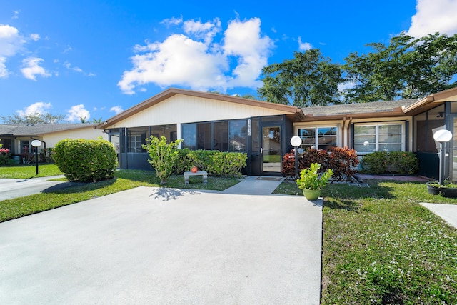 single story home featuring a front lawn and a sunroom