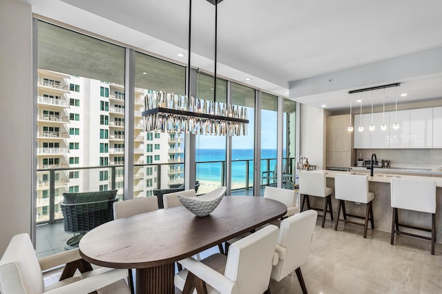 dining area featuring sink, a water view, light tile patterned floors, and floor to ceiling windows