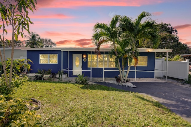 ranch-style home featuring fence, stucco siding, a yard, and driveway