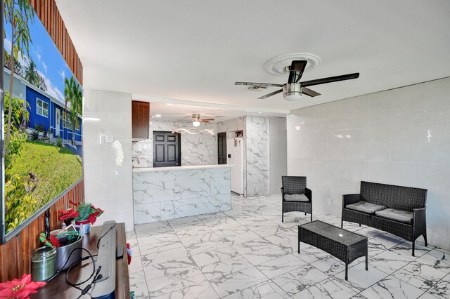 interior space featuring tile walls, ceiling fan, visible vents, and marble finish floor