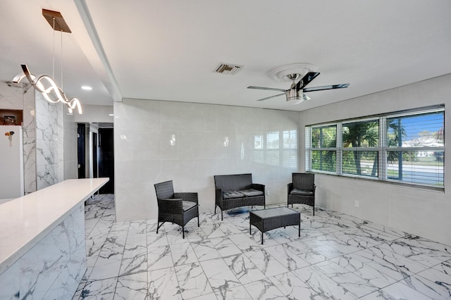 living room with marble finish floor, ceiling fan, tile walls, and visible vents