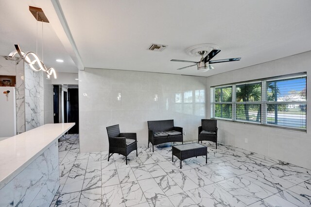 unfurnished room featuring marble finish floor, ceiling fan, and tile walls