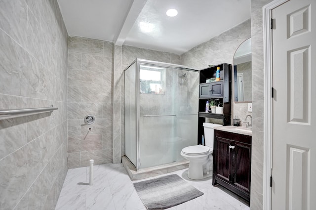 bathroom with tile walls, a stall shower, vanity, toilet, and marble finish floor