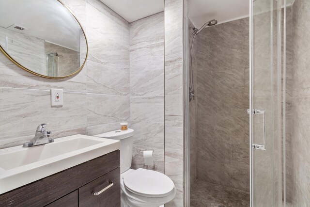 bathroom featuring vanity, tile walls, a stall shower, and toilet