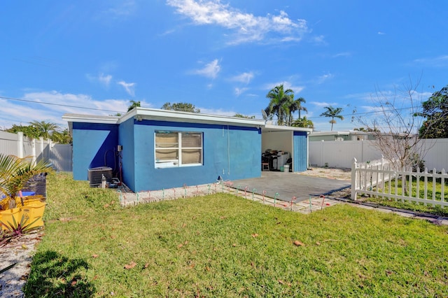 back of house featuring a yard, central AC, a fenced backyard, and stucco siding