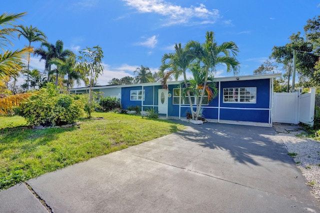 ranch-style house with a front lawn, fence, and concrete driveway