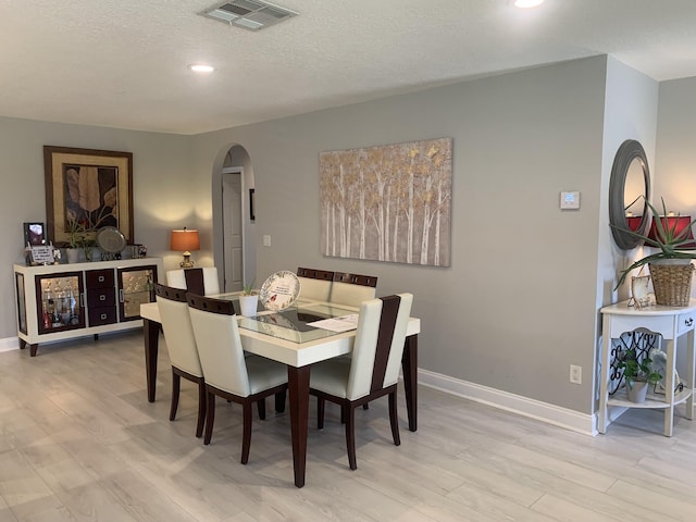 dining area featuring a textured ceiling and light wood-type flooring