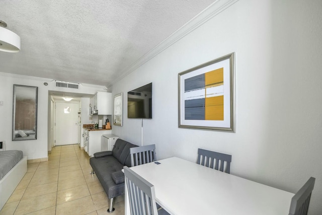 dining space with light tile patterned flooring, ornamental molding, and a textured ceiling