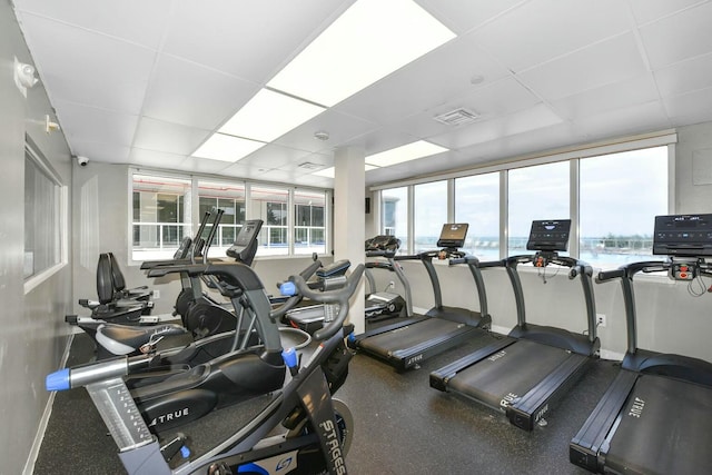 gym featuring a water view and a paneled ceiling