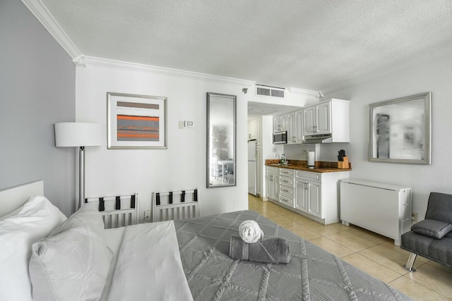 interior space with light tile patterned flooring, sink, white fridge, crown molding, and a textured ceiling