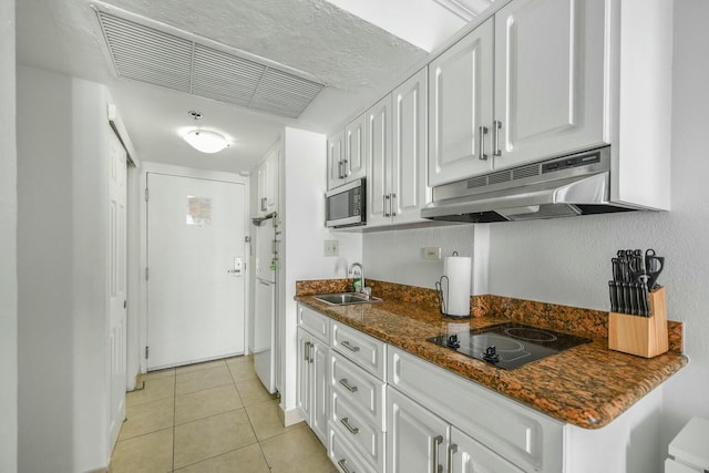 kitchen featuring light tile patterned flooring, white cabinetry, sink, dark stone counters, and black electric cooktop