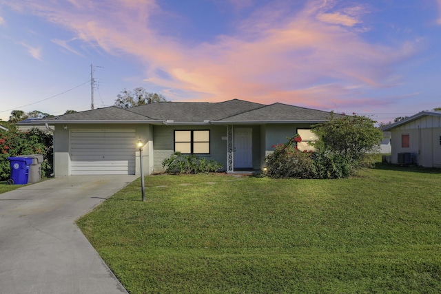 single story home featuring cooling unit, a yard, and a garage