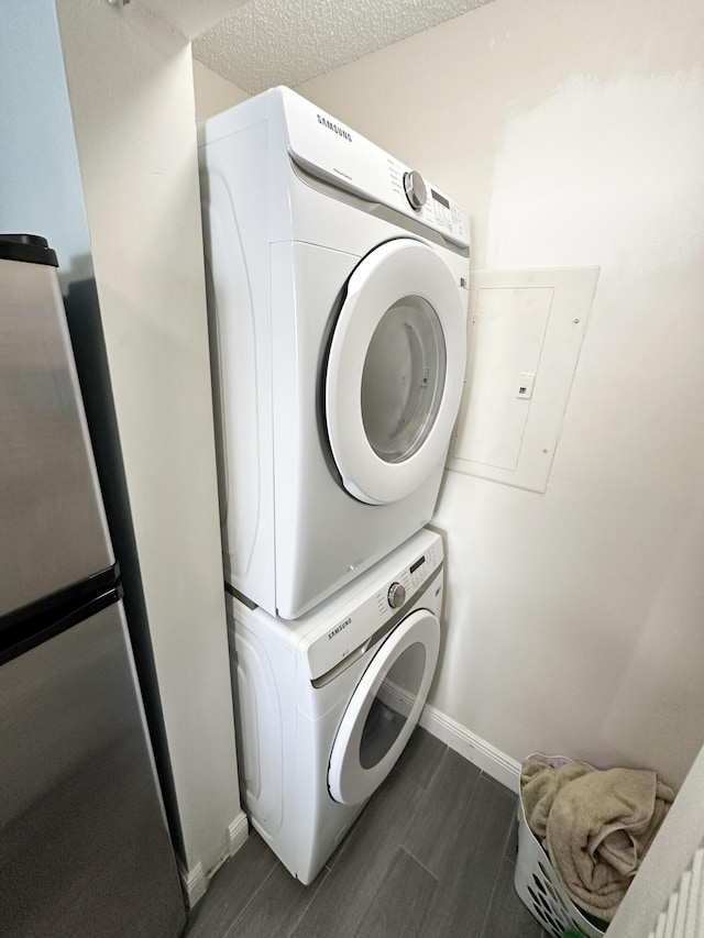 clothes washing area with stacked washer / dryer, a textured ceiling, and dark hardwood / wood-style flooring