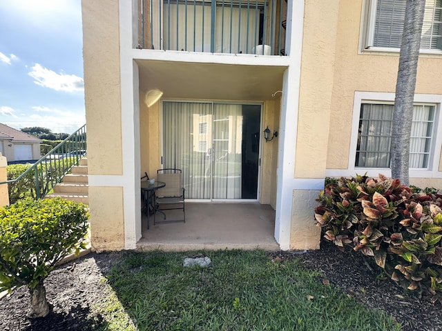 entrance to property featuring a patio and a balcony