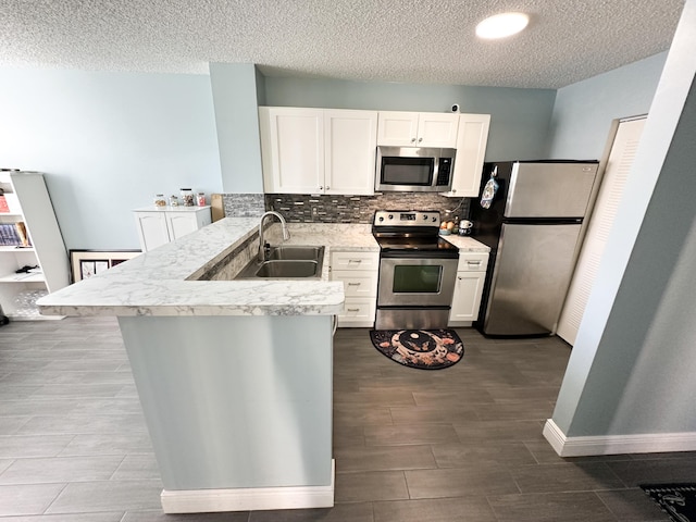 kitchen with sink, appliances with stainless steel finishes, white cabinets, decorative backsplash, and kitchen peninsula