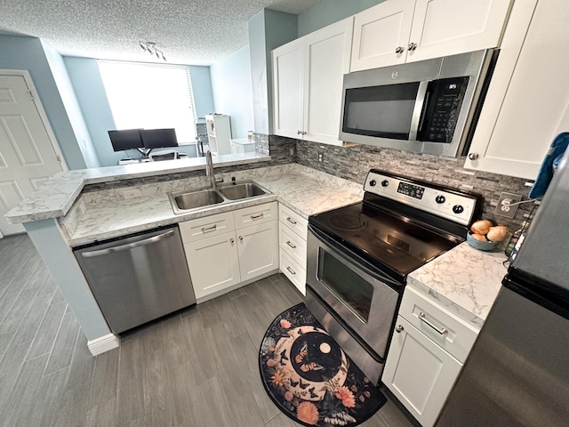 kitchen with sink, white cabinetry, kitchen peninsula, stainless steel appliances, and backsplash