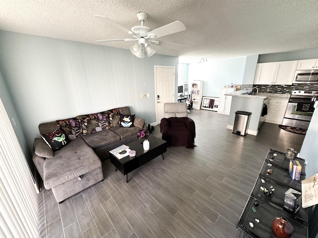 living room with sink, a textured ceiling, and ceiling fan