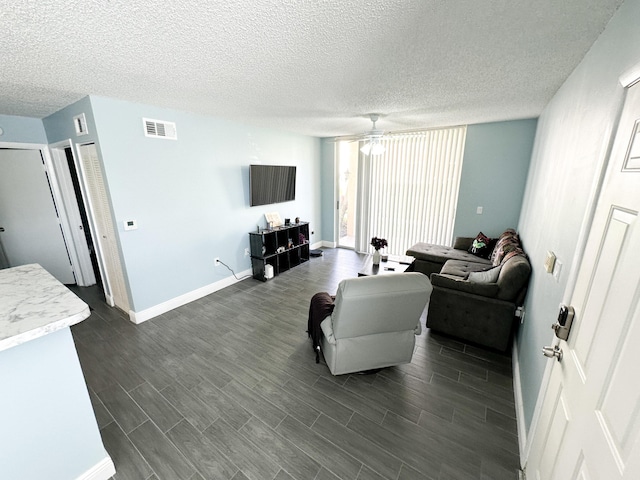 living room featuring ceiling fan, dark hardwood / wood-style flooring, and a textured ceiling