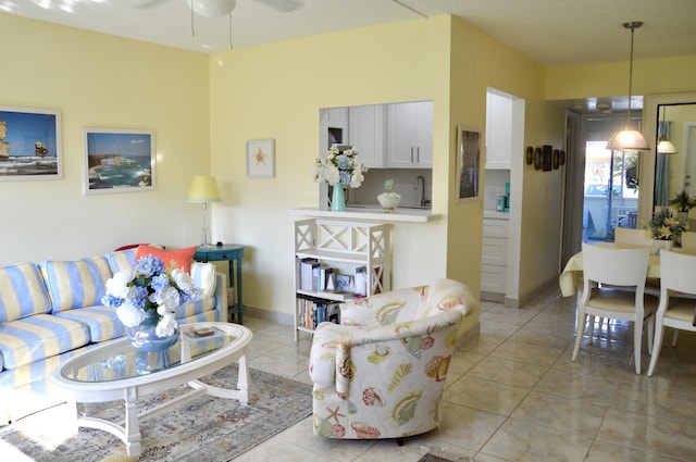 living room with sink, light tile patterned floors, and ceiling fan