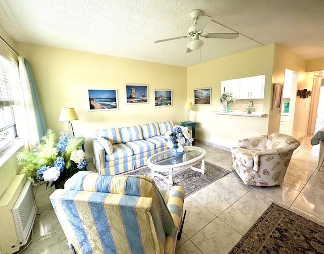 living area featuring baseboards, a ceiling fan, and a textured ceiling