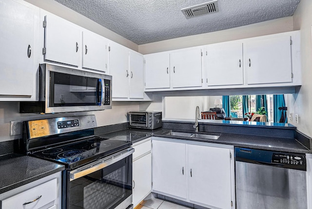 kitchen featuring appliances with stainless steel finishes, sink, white cabinets, and a textured ceiling