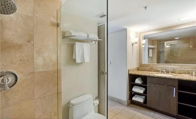 bathroom with tiled shower, vanity, toilet, and tile patterned floors