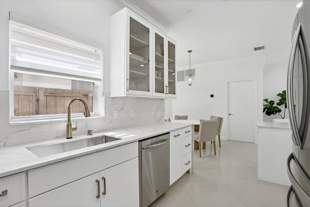 kitchen with sink, stainless steel appliances, tasteful backsplash, white cabinets, and decorative light fixtures