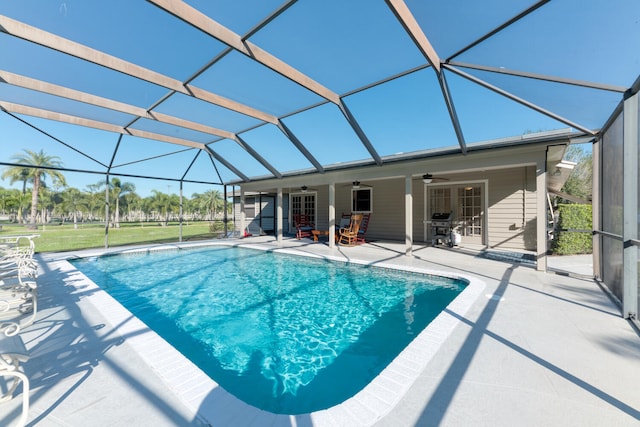 view of pool with a patio, ceiling fan, and glass enclosure