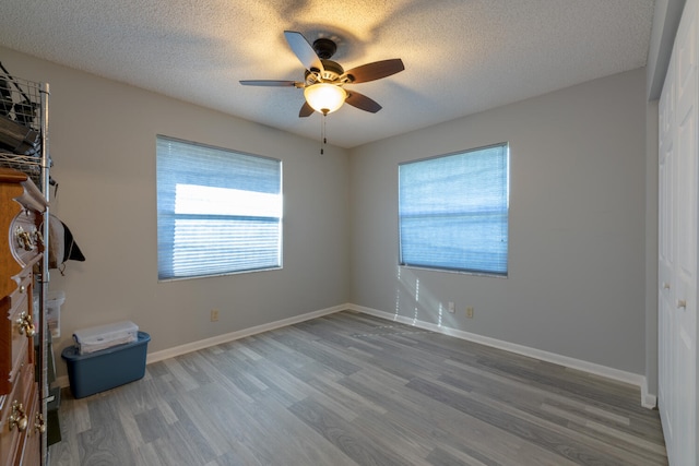 unfurnished bedroom featuring hardwood / wood-style flooring, ceiling fan, and a textured ceiling