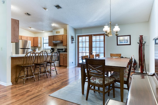 dining space featuring lofted ceiling, a textured ceiling, light wood-type flooring, and french doors